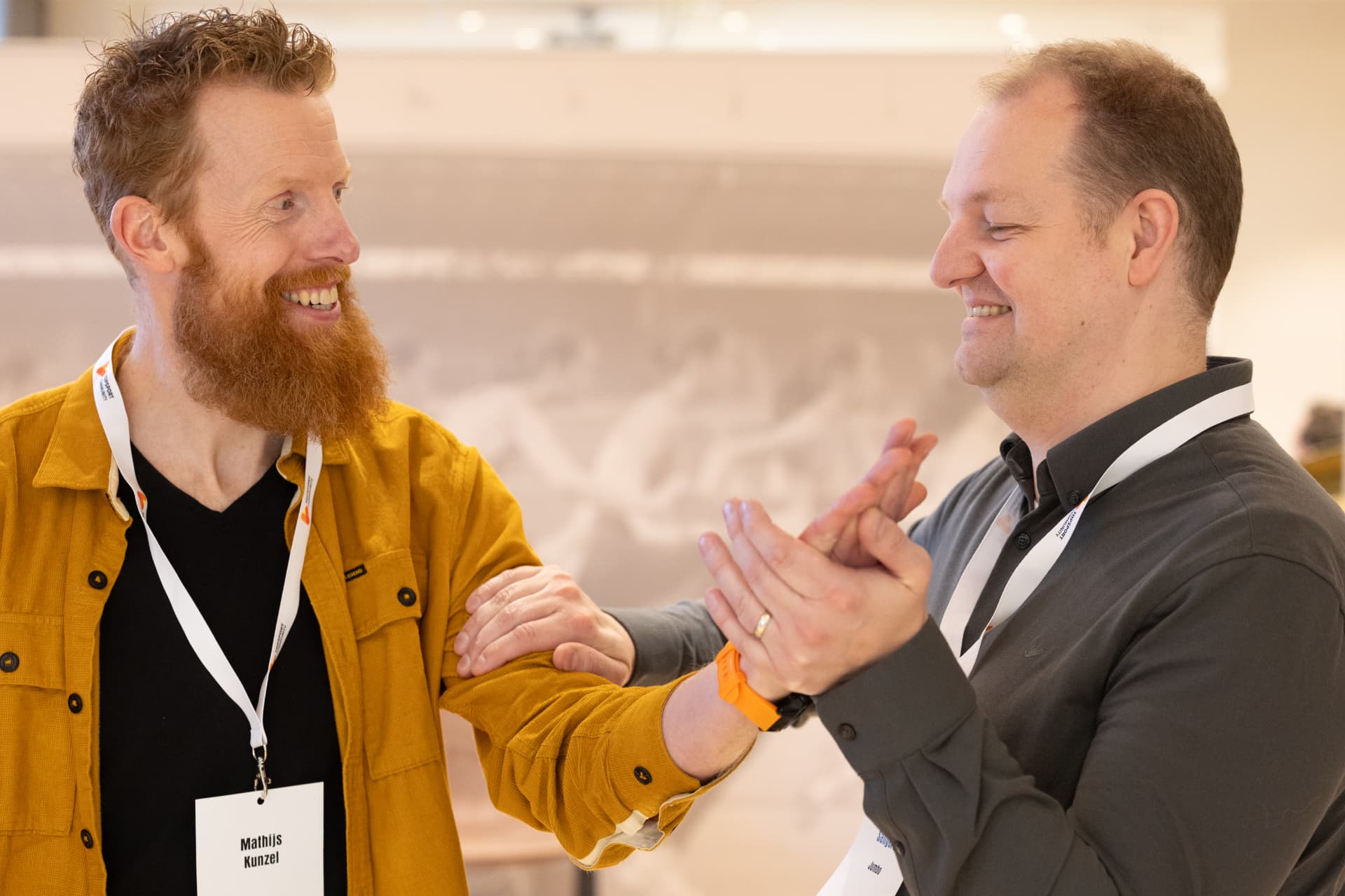 Twee deelnemers oefenen lachend samen tijdens een teambuilding workshop